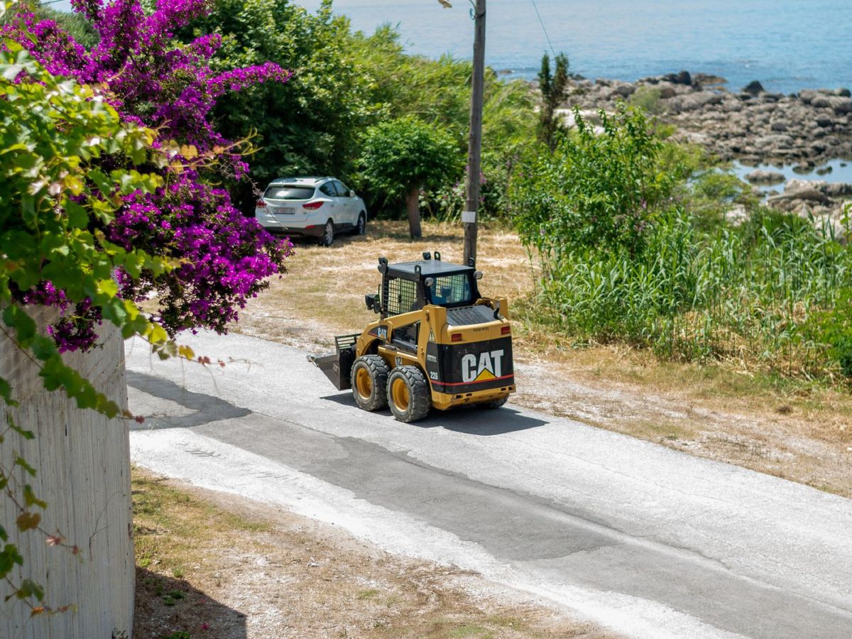 Minipala gommata con benna su una strada vicino al mare